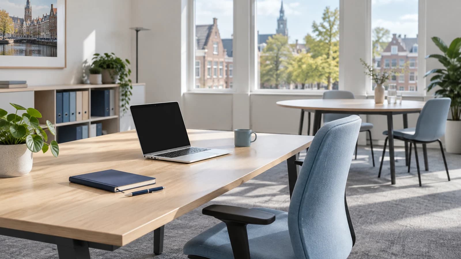 Lichte werkplek met een lege bureaustoel, laptop en notitieboek bij het raam.